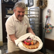 Bäckermeister Thomas Zimmer hält ein Patenbündel in den Händen. Dieses besteht aus dem Eierring, gefüllt mit 12 Eiern, und wird traditionell in einem weißen Leintuch übergeben. Foto: Hannah Neudecker