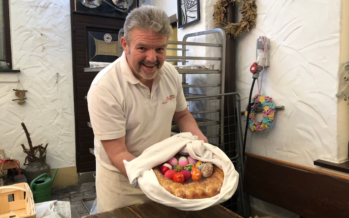 Bäckermeister Thomas Zimmer hält ein Patenbündel in den Händen. Dieses besteht aus dem Eierring, gefüllt mit 12 Eiern, und wird traditionell in einem weißen Leintuch übergeben. Foto: Hannah Neudecker