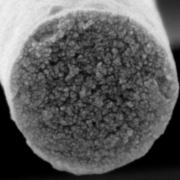 Rasterelektronenmikroskopische Aufnahme des Querschnitts einer Faser des neuen Vliesstoffes: In der Kohlenstoff-Matrix sind mit Keramik gefüllte Bereiche gleichmäßig verteilt. Bild: UBT.