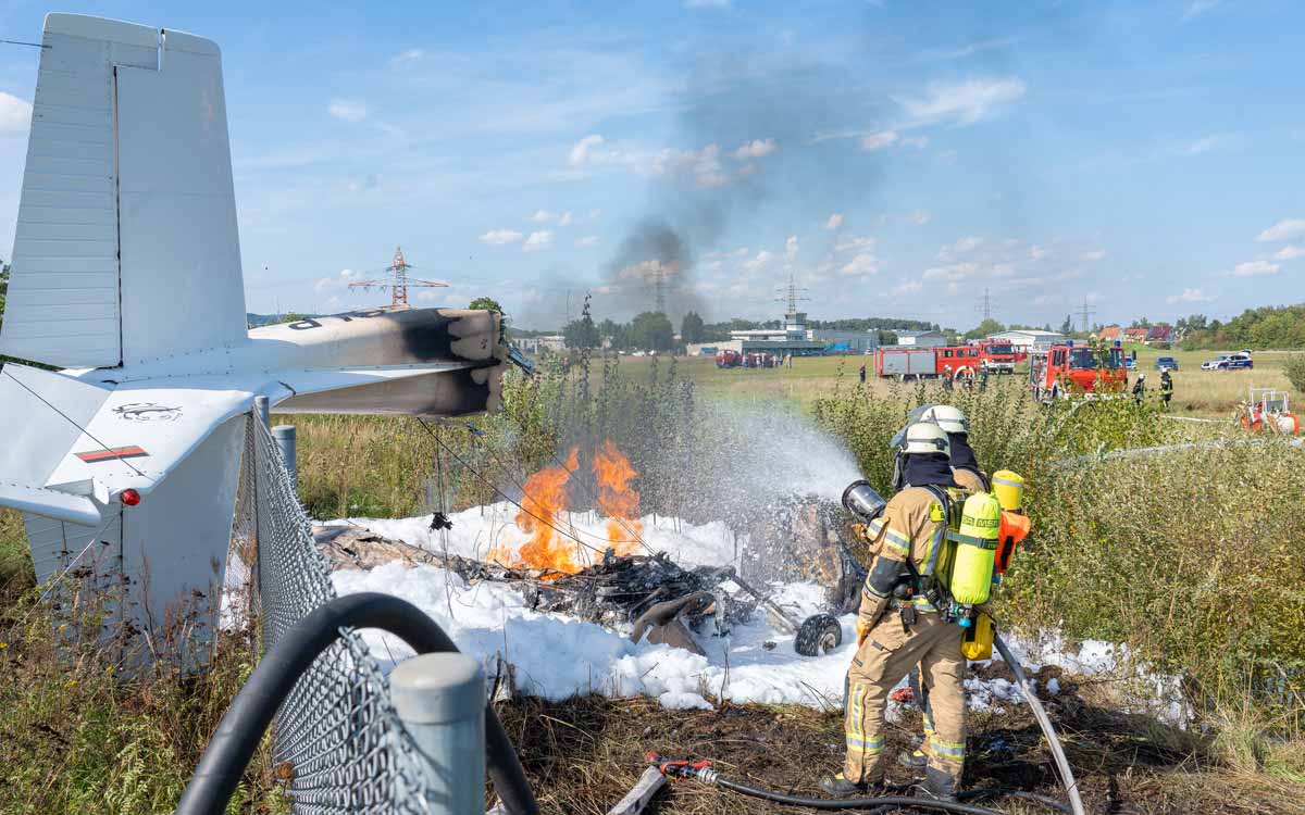 Feuerwehrkameraden löschen das Wrack am Bamberger Flugplatz. Foto: NEWS5 / Merzbach