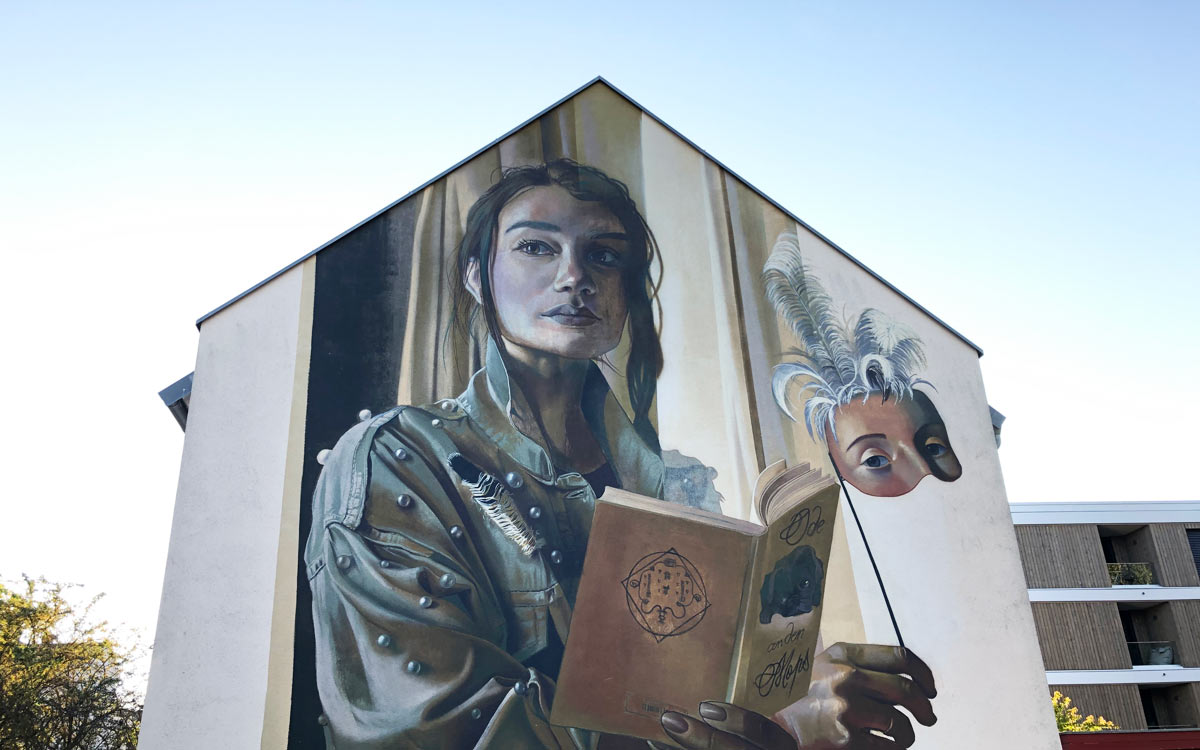 Ein großformatiges Street-Art-Bild des Künstlers Case Maclaim in der Bayreuther Badstraße. Es thematisiert das Leben der Markgräfin Wilhelmine - das Buch verweist beispielsweise auf den 