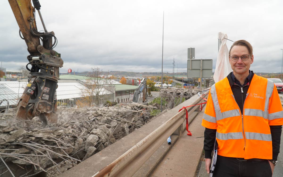 Marco Weber von der Autobahn GmbH ist zufrieden mit dem Fortschritt an der Bayreuther Hochbrücke. Neben ihm reißt ein Bagger die erste Rampe ab. Foto: Johannes Pittroff