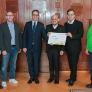 Regierungspräsident Florian Luderschmid (3.v.l.) übergibt den symbolischen Spendenscheck an Dekan Jürgen Hacker und Pfarrer Christian Karl Steger für die Initiative 